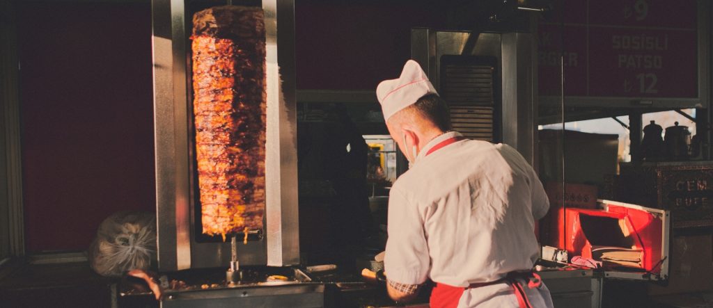 Döner kebab being sliced on a vertical spit by Döner Master